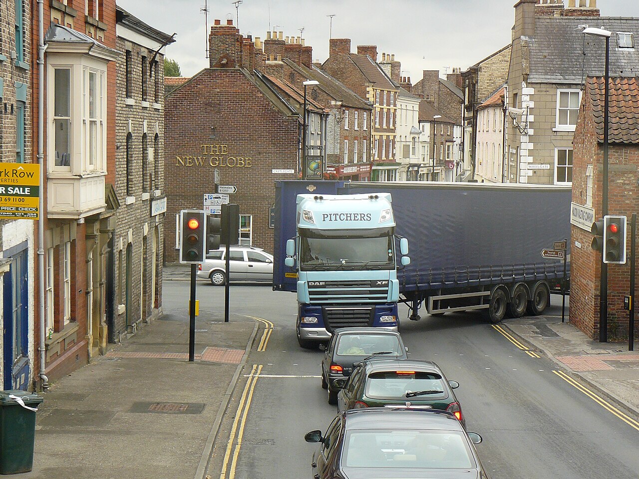 Articulated tractor unit and curtain-side semi-trailer swinging through a tight town junction