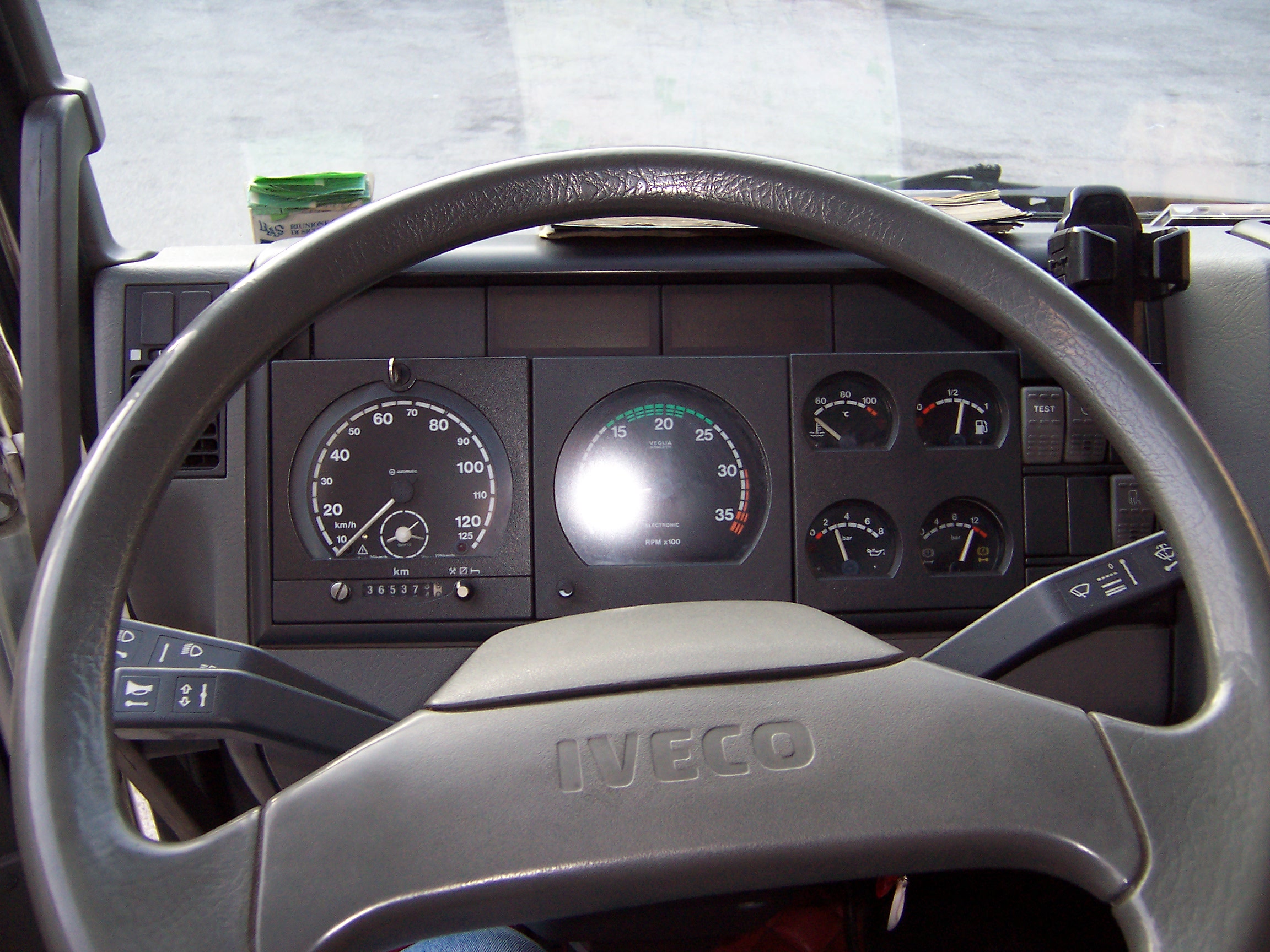 Interior dashboard of a commercial Iveco truck showing the steering wheel and instrument panel