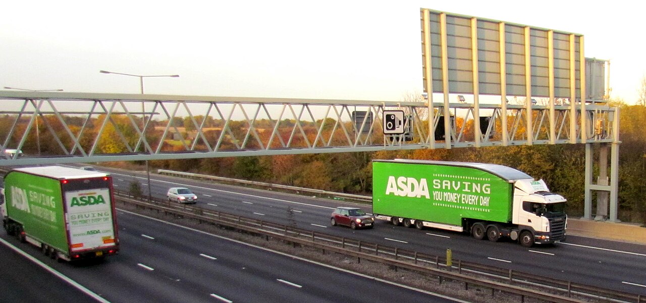 Laden heavy goods vehicles on a multi-lane motorway under a gantry