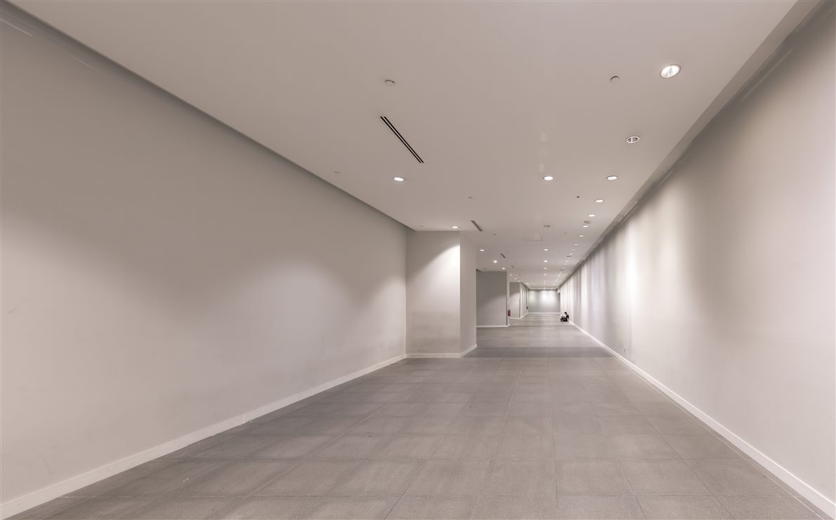 Long tiled corridor in strong perspective, equal floor tiles shrinking toward the far end
