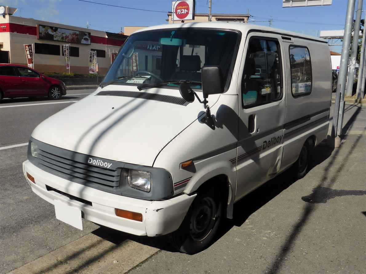 Small white delivery van parked at a curb, compact body about four and a half meters long
