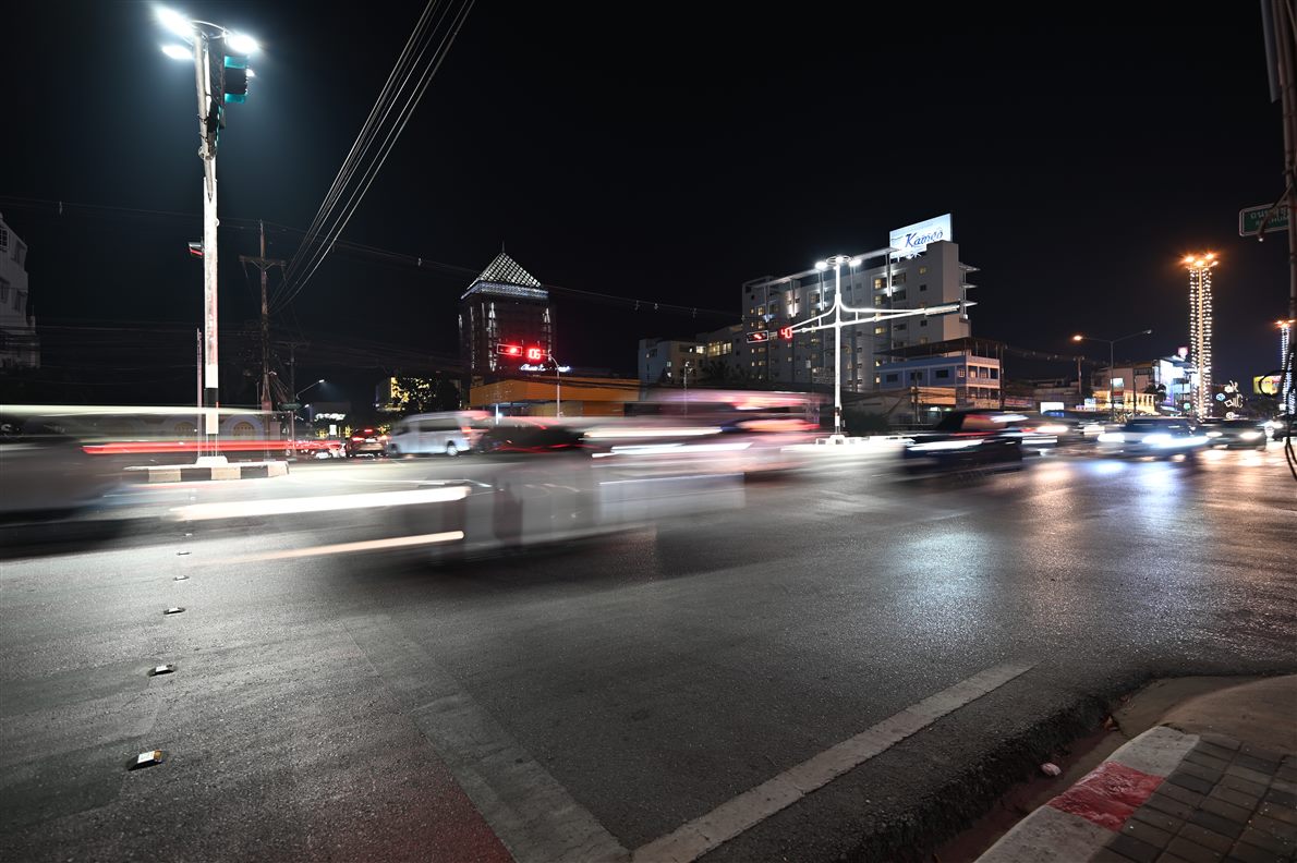 Busy night intersection with streetlights and the streaked light trails of moving vehicles under a black sky