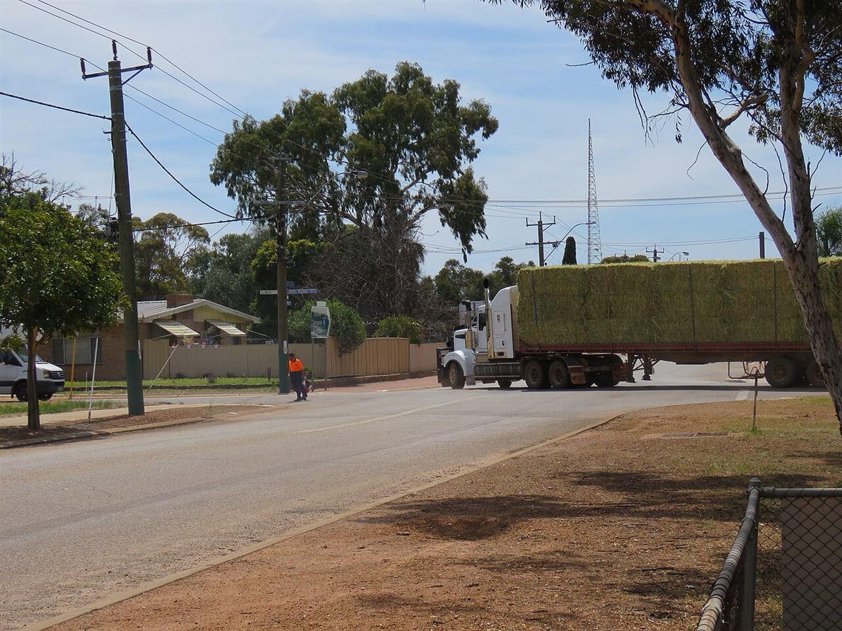 A semi-trailer truck turning across a road intersection, the cab swung onto the new heading with the loaded trailer still angled behind it