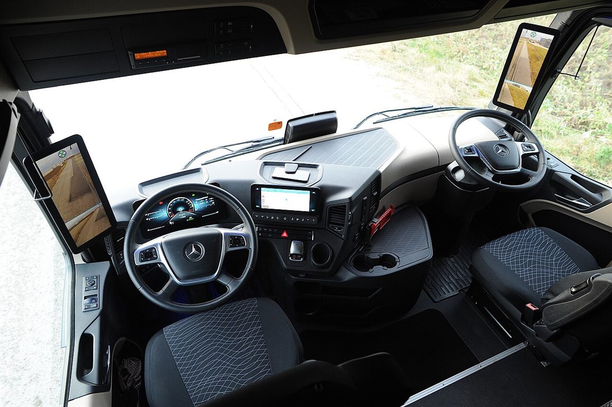 The interior of a truck cab showing two digital mirror screens on the pillars, a central touchscreen and a digital instrument cluster
