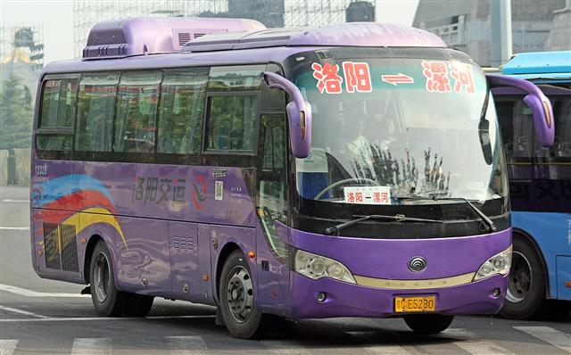 A purple Yutong coach at a station with a route board reading Luoyang to Luohe
