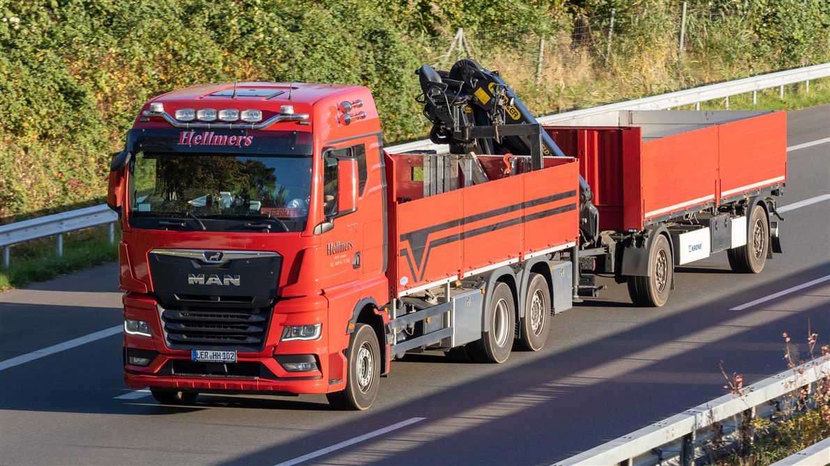 Red MAN TGX flatbed truck with a loader crane
