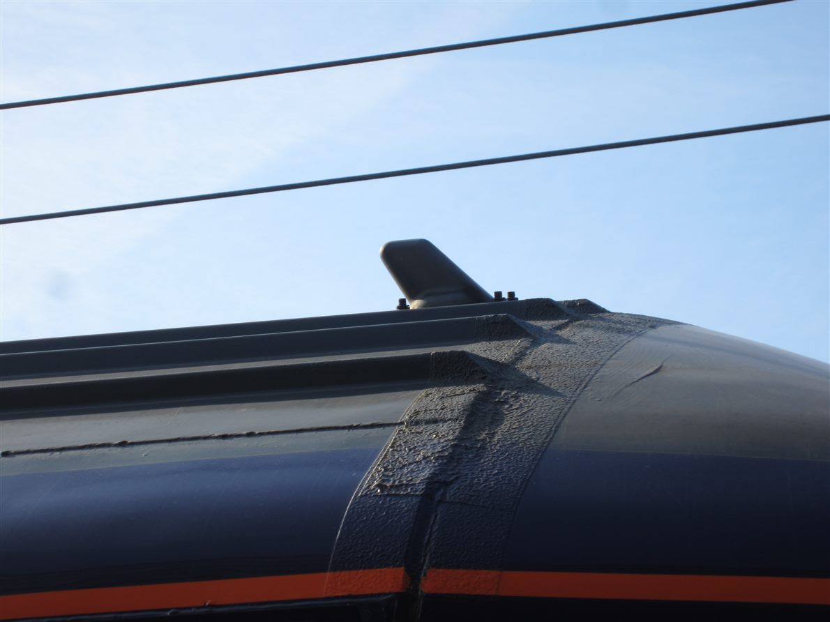 Shark-fin cellular antenna mounted on a vehicle roof against the sky